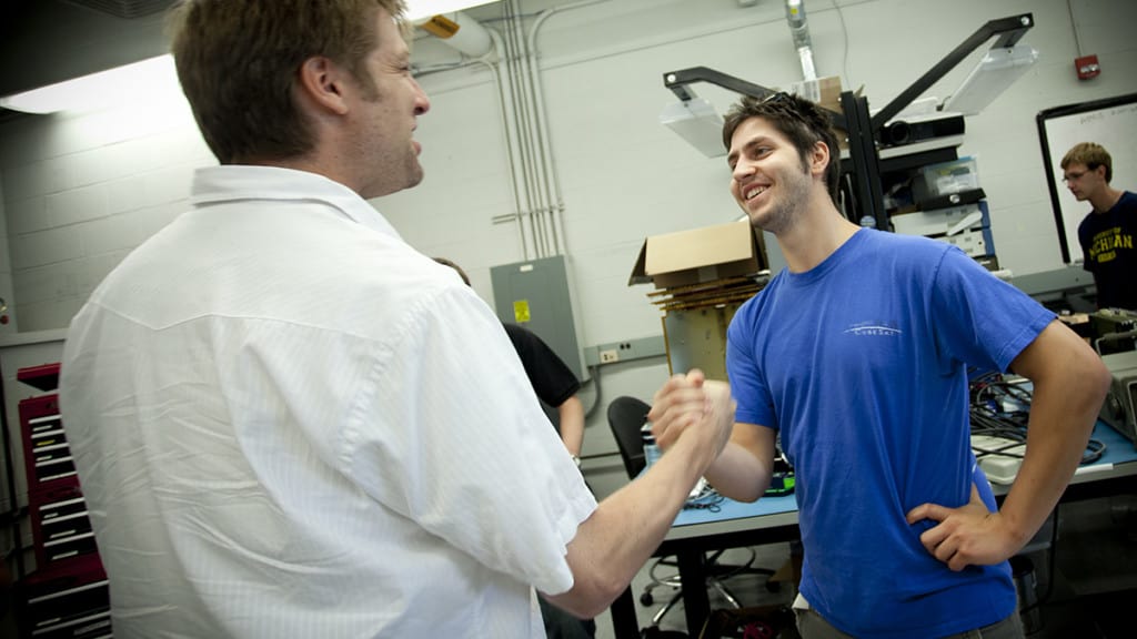 grad student with faculty shaking hands in the lab