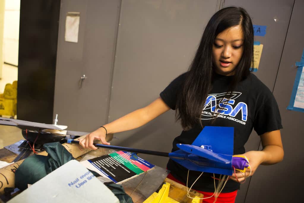 diverse female student adjust a wing of the model